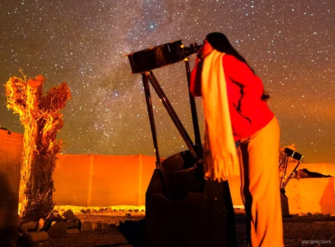 Excursions dans l'Atacama, voyageuse regardant dans un grand télescope sous un ciel étoilé du désert