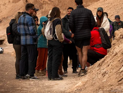 Grupo de passeios no Atacama com casacos quentes reunido em volta do guia numa trilha do Valle de la Luna