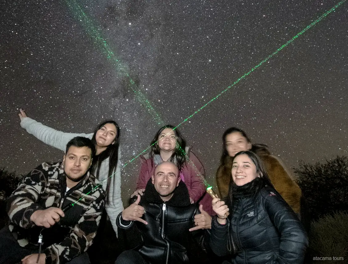 Tours astronomiques dans l'Atacama, groupe souriant sous le ciel nocturne avec des lasers verts