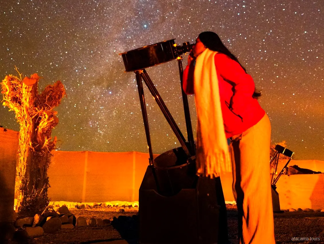 Tour ad Atacama, viaggiatrice che guarda in un grande telescopio sotto il cielo stellato del deserto
