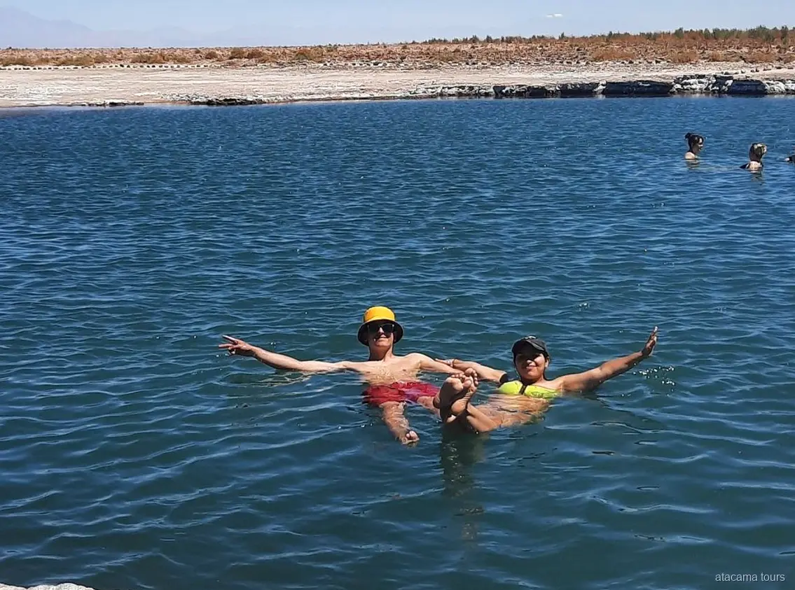 Tour nel deserto di Atacama, due visitatori galleggiano a braccia aperte nell'acqua salata di Laguna Cejar