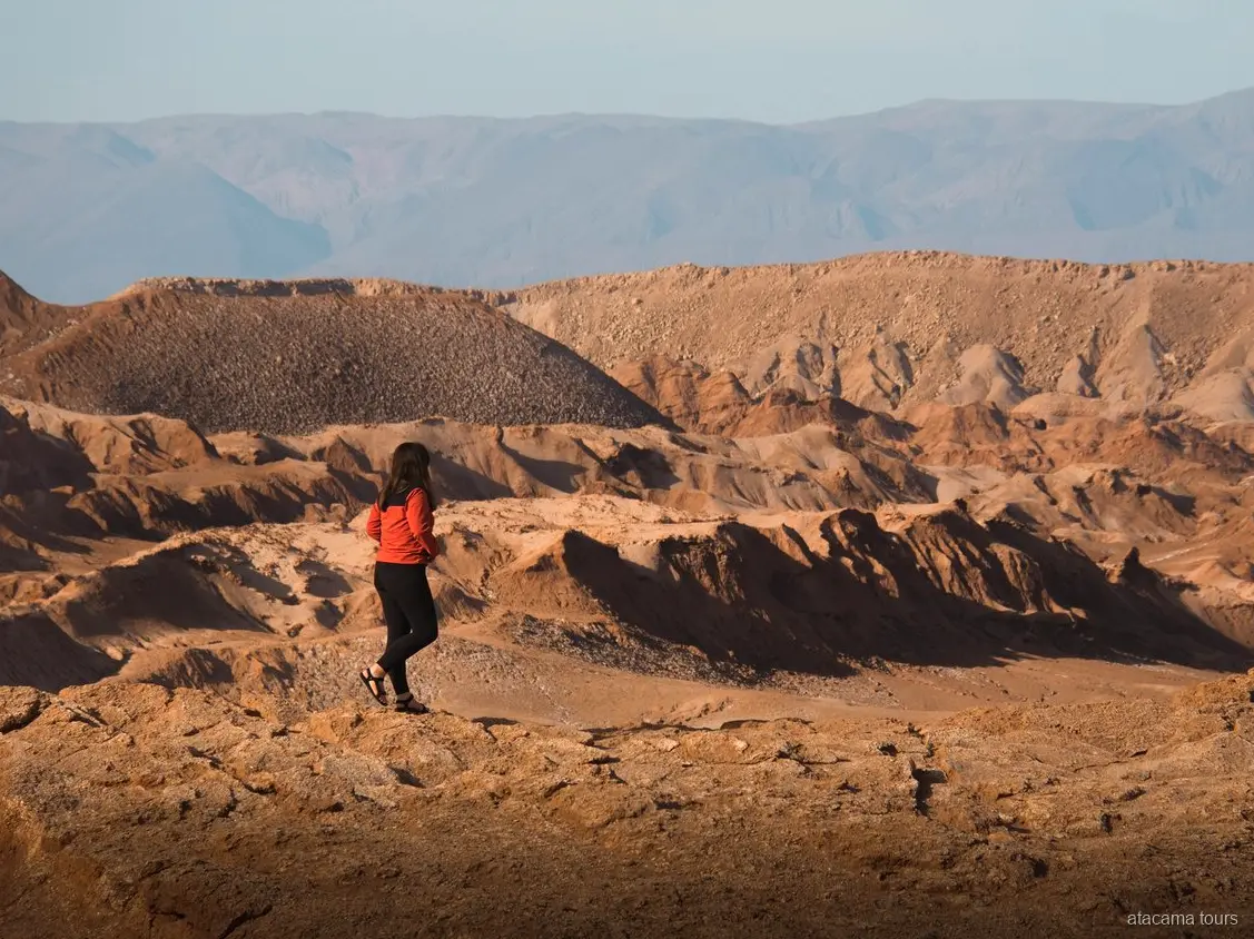 Tour ad Atacama a Baltinache, escursionista in giacca rossa davanti a creste erose del deserto
