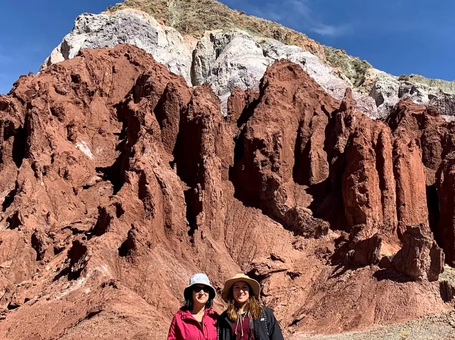 Excursions dans l'Atacama au Valle del Arcoiris, deux visiteurs en chapeau devant des aiguilles de roche rouge